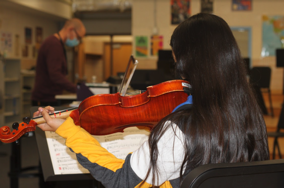 Back of student playing violin in class